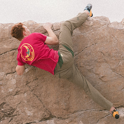 A male climber topping out on a boulder