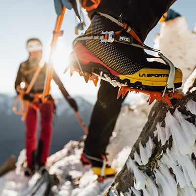 A closeup of two climbers ascending a steep, icy mountain face