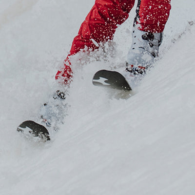 A closeup of a skier going down hill in deep snow