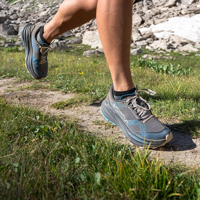 A closeup of a female runner's shoes on a mountain trail