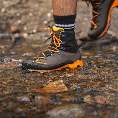 A closeup of a male hiker crossing a shallow stream
