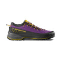 A side view shows the La Sportiva TX4 EVO Women's hiking shoe in purple, black, and yellow, highlighting its rugged Vibram Megagrip sole, laces, and LA SPORTIVA branding for maximum stability.