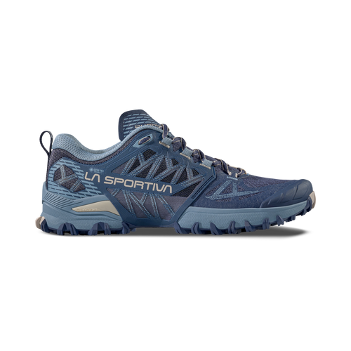 A blue La Sportiva Bushido III GTX Women’s trail running shoe is shown in profile against a white background, featuring rugged tread, breathable mesh panels, and bold “LA SPORTIVA” text on the side. This model incorporates Gore-Tex technology for superior waterproof protection.