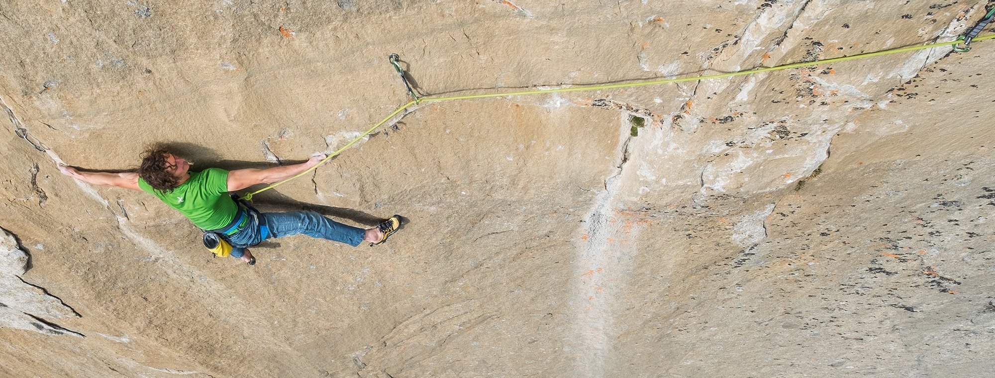 Person rock climbing on a steep cliff face with a rope.