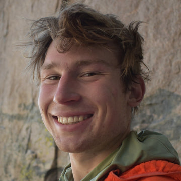 Person with a smile in front of a stone wall