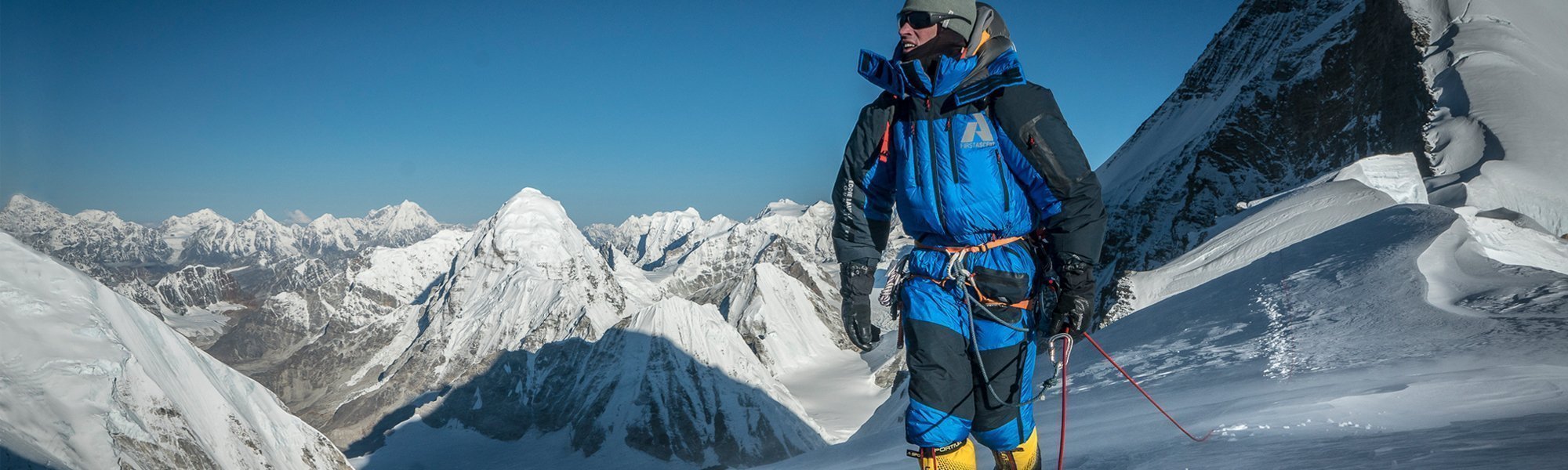 Person in winter clothing with mountain equipment on a snowy mountain peak