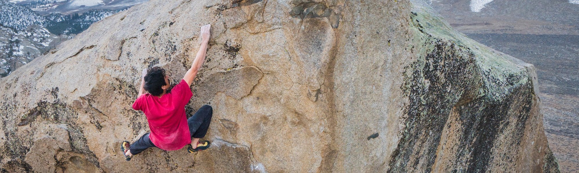 Person climbing a rocky mountain face with a scenic background