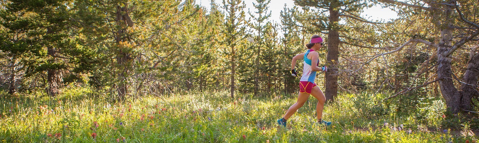 Person running through a forest with trees and greenery in the background