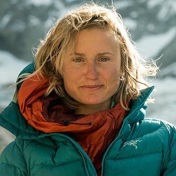 Person wearing a teal jacket with a red scarf in a snowy landscape