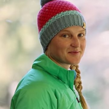 Person wearing a colorful knit hat and green jacket outdoors