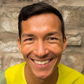 Man wearing a bright yellow shirt against a stone wall background