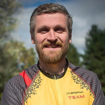 Man wearing a yellow and gray sports jacket with 'La Sportiva Team' branding outdoors.