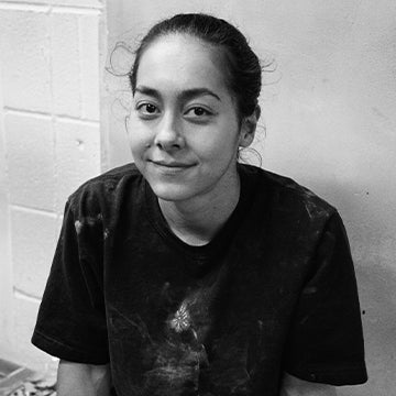 Person wearing a black t-shirt with stains against a tiled wall background