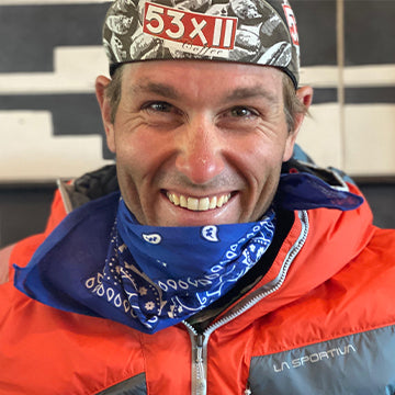 Person wearing a red jacket, blue bandana, and camouflage cap with '53X11' logo.