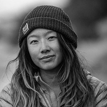 Black and white photo of a person wearing a beanie with a logo.