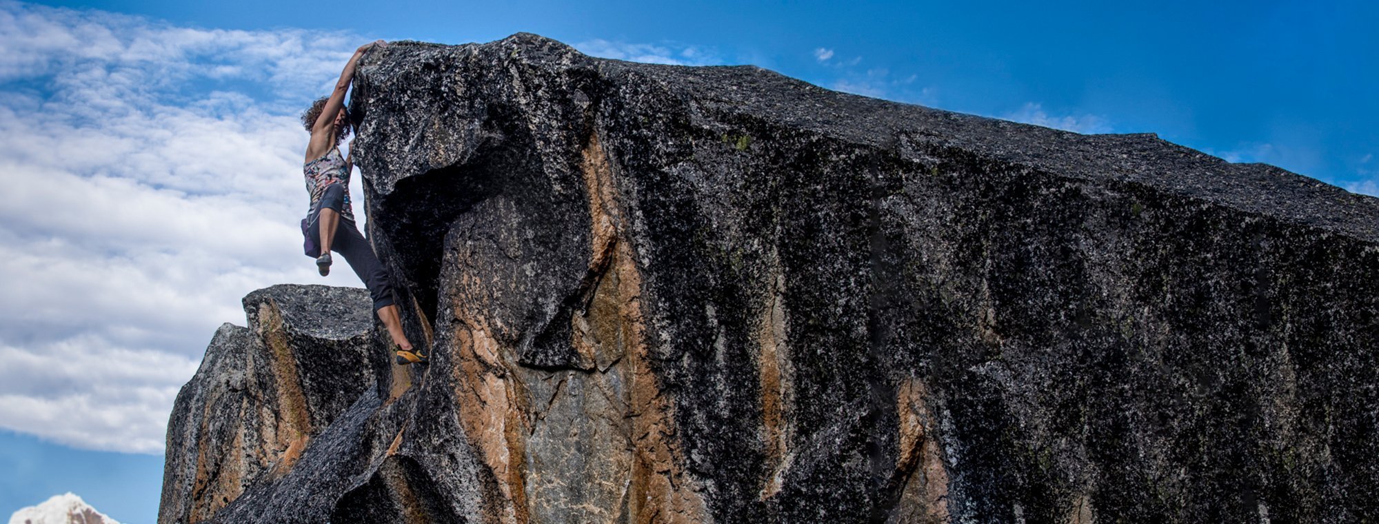 Close-up of a large rock formation with a blue sky and clouds in the background