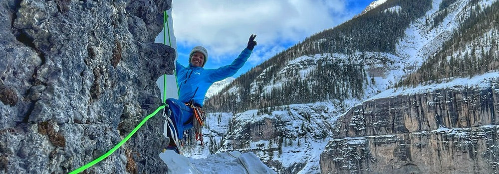 Person slacklining on a rock with a snowy mountain landscape in the background
