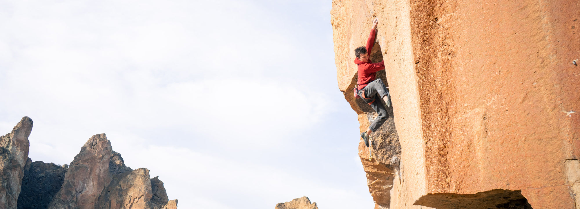 Person climbing a rock face with other rocky formations in the background