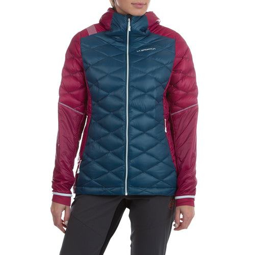 Une femme portant la veste Aiguille Down Jacket de La Sportiva - une veste à capuche de couleur sarcelle et bordeaux avec duvet recyclé, motif matelassé et logo sur la poitrine - se tient debout sur un fond blanc.