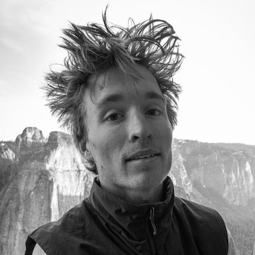 Person with spiky hair standing in front of a mountainous landscape