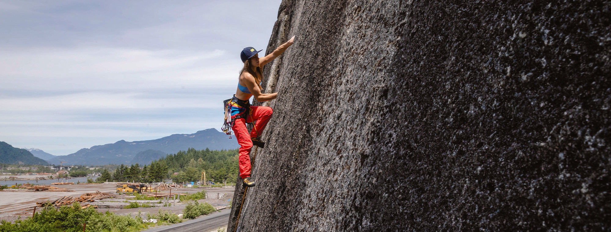 Person rock climbing on a large cliff with a scenic background