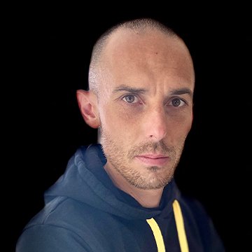 Man wearing a dark hoodie with a yellow drawstring against a black background
