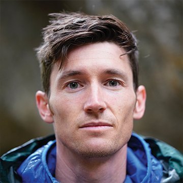 Man wearing a blue jacket with a blurred natural background