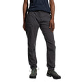 A person wearing La Sportiva Labyrinth Pants Women's (2025) with an adjustable waistband, a navy blue shirt, and black hiking shoes stands with one hand by their side and the other on their thigh. Photo is cropped at the shoulders.