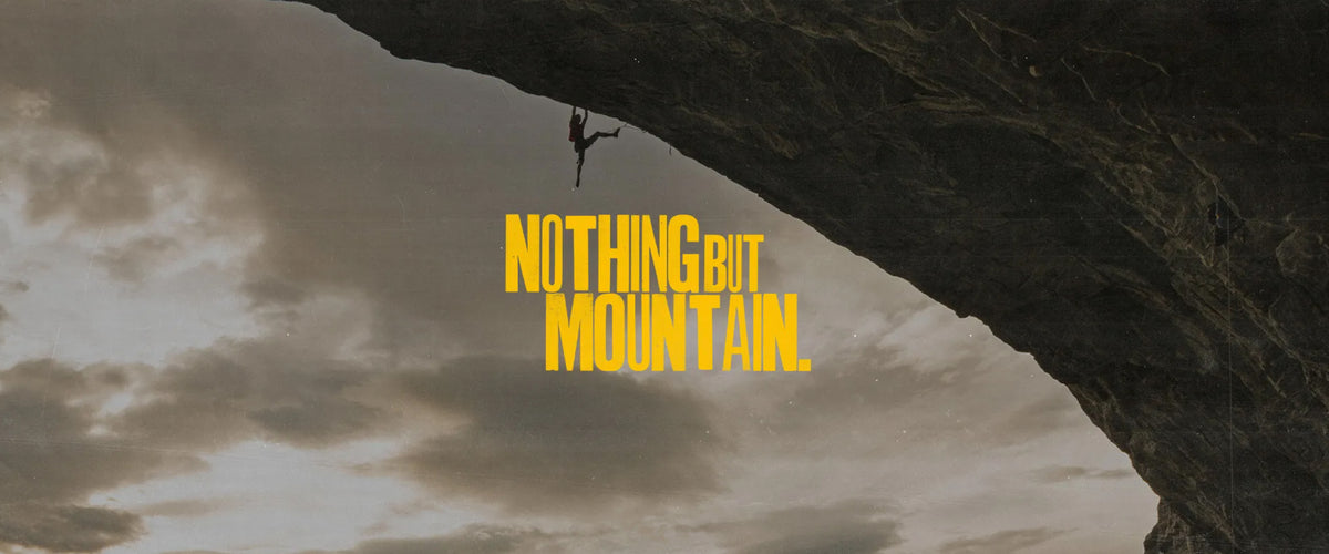 A rock climber on a cliff with a text overlay that says "Nothing but Mountain."