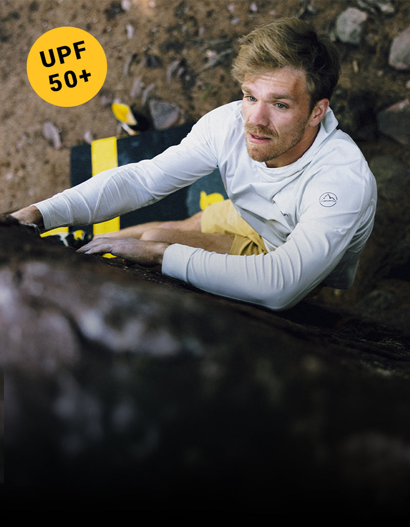A man climbing in a white Cloud Shadow Sun Hoody with a UPF 50+ badge in the corner