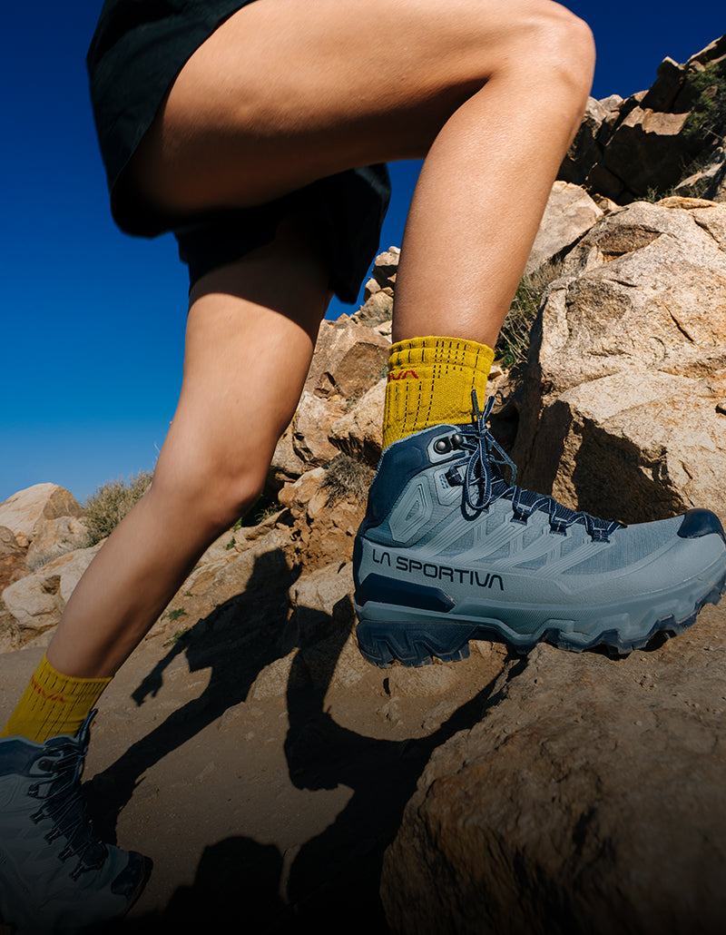 A knee-down image of a woman hiking while wearing the Ultra Raptor 3 hiking boors.