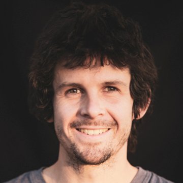 Man with a beard and casual clothing against a dark background