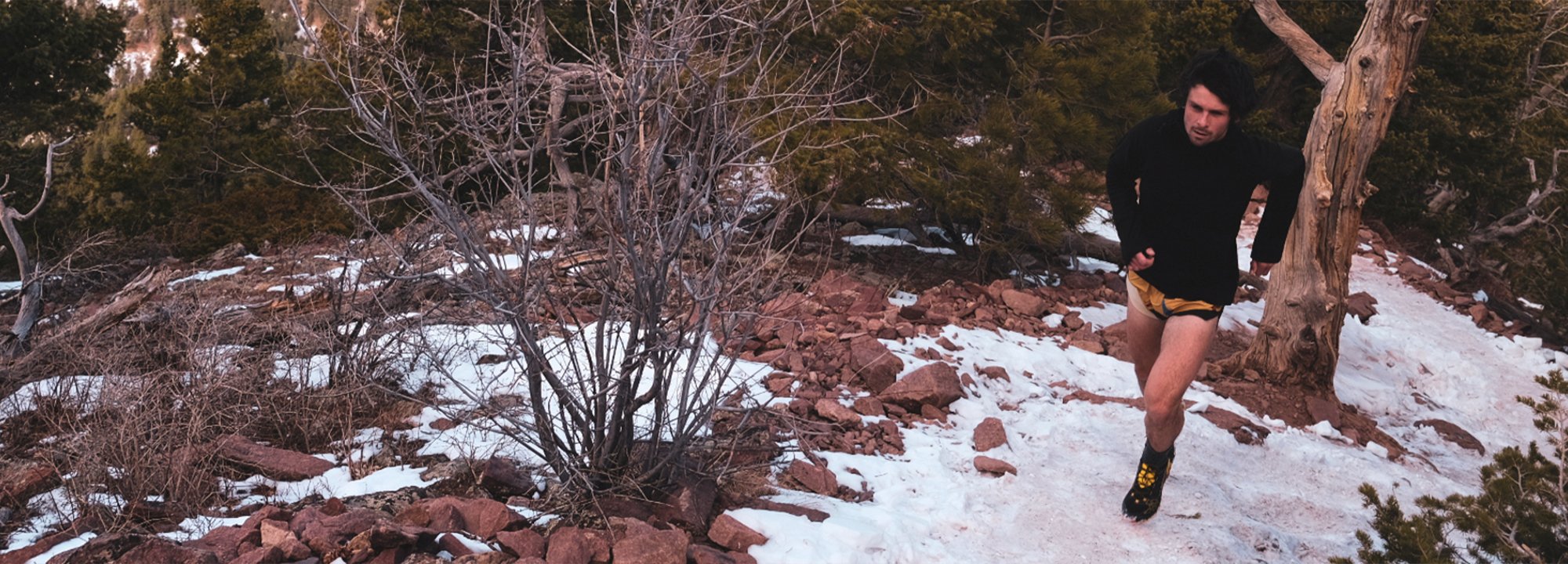 Person running on a snowy trail in a forested area