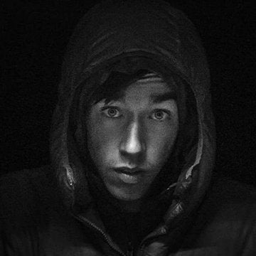 Person wearing a hooded garment in a dark setting