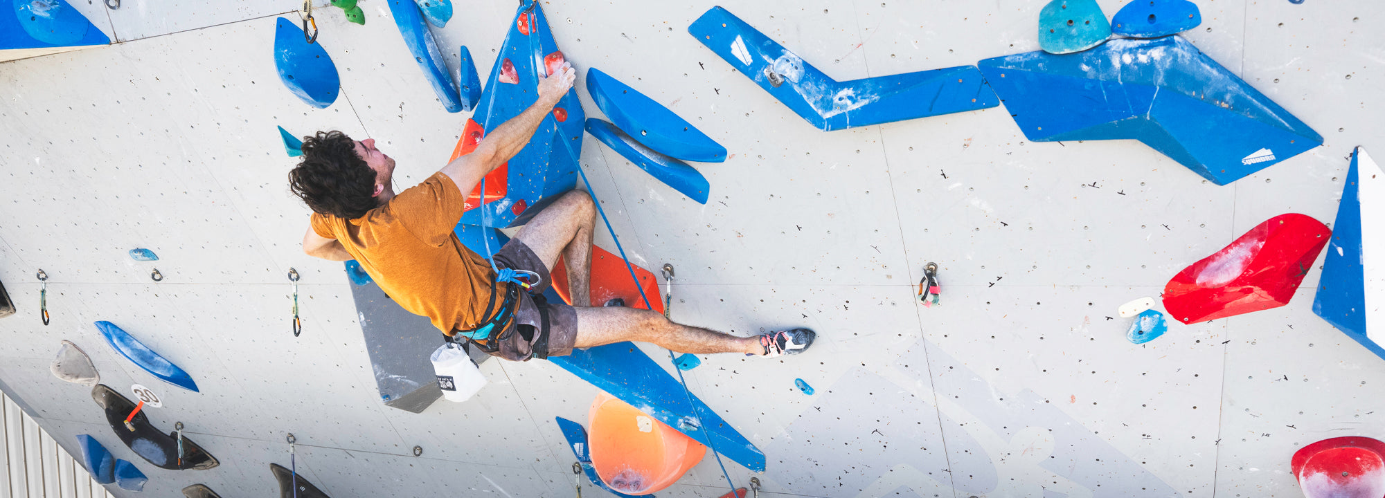 Person climbing a colorful indoor rock wall.