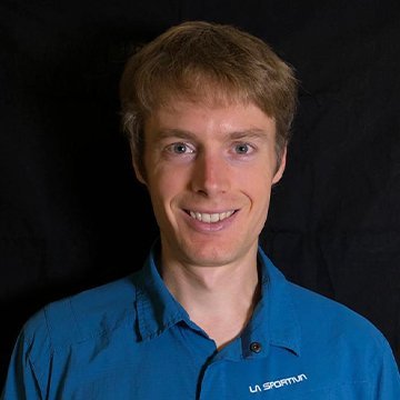Man wearing a blue shirt with a logo against a black background