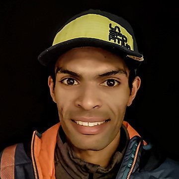 Person wearing a cap and jacket with a dark background