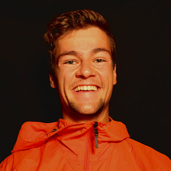 Man wearing an orange jacket against a black background