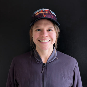 Person wearing a cap and jacket against a black background