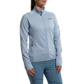 Une femme portant une veste légère La Sportiva Chill Jacket Women's bleu clair avec une fermeture éclair complète et un logo sur la poitrine, associée à un pantalon bleu assorti, se tient debout sur un fond blanc.