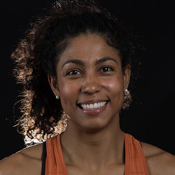 Woman wearing an orange sports bra against a black background