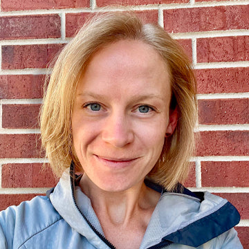 Person with blonde hair standing in front of a brick wall