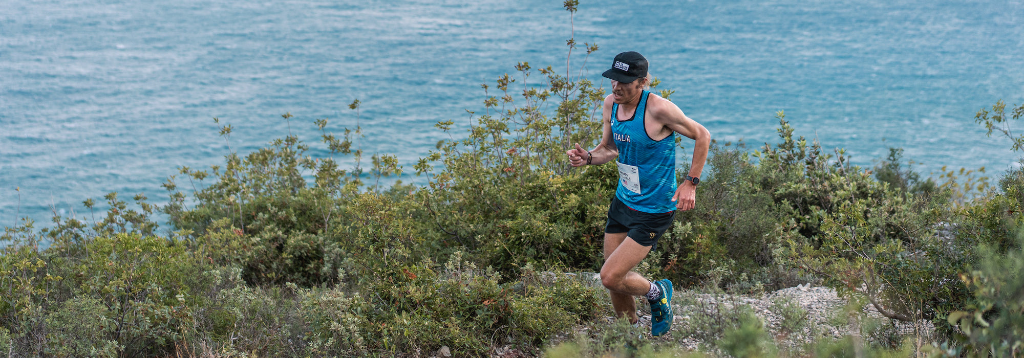 Man running on a trail with ocean in the background