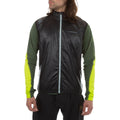 A man wears the La Sportiva Blizzard Windbreaker Vest in black over a green and yellow long-sleeve shirt with black pants, posing against a plain white background.