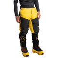 A person wearing La Sportiva Olympus Tech Down Pants Men's in yellow and black, inspired by Himalayan expeditions, stands against a white background. Only the lower half of the body is visible.