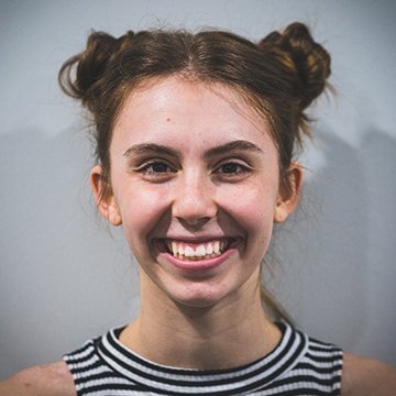 Person with hair styled in buns against a plain background