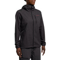 A woman wearing the La Sportiva Wall Breeze Stretch Jacket in black, featuring a helmet-compatible hood, chest zipper pocket, and small logo on the left side, with matching pants, stands against a white background.