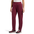 Wearing La Sportiva Podium Pants Women’s in maroon—styled like sweatpants—a person stands against a white background, showing only their lower body. Their outfit is completed with a white top and maroon and black sneakers.