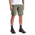 Une personne est représentée de la taille vers le bas portant un short La Sportiva Talus Men's en vert olive, associé à un T-shirt blanc, des chaussettes bleu marine et des chaussures de randonnée noires. La pose décontractée met en valeur la conception du short en tissu recyclé.