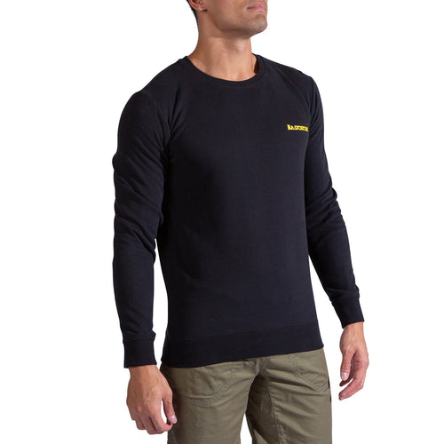Un homme portant le sweat-shirt La Sportiva Climbing on the Moon en noir, avec un petit logo jaune sur la poitrine gauche, et un pantalon vert olive, se tient sur un fond blanc.